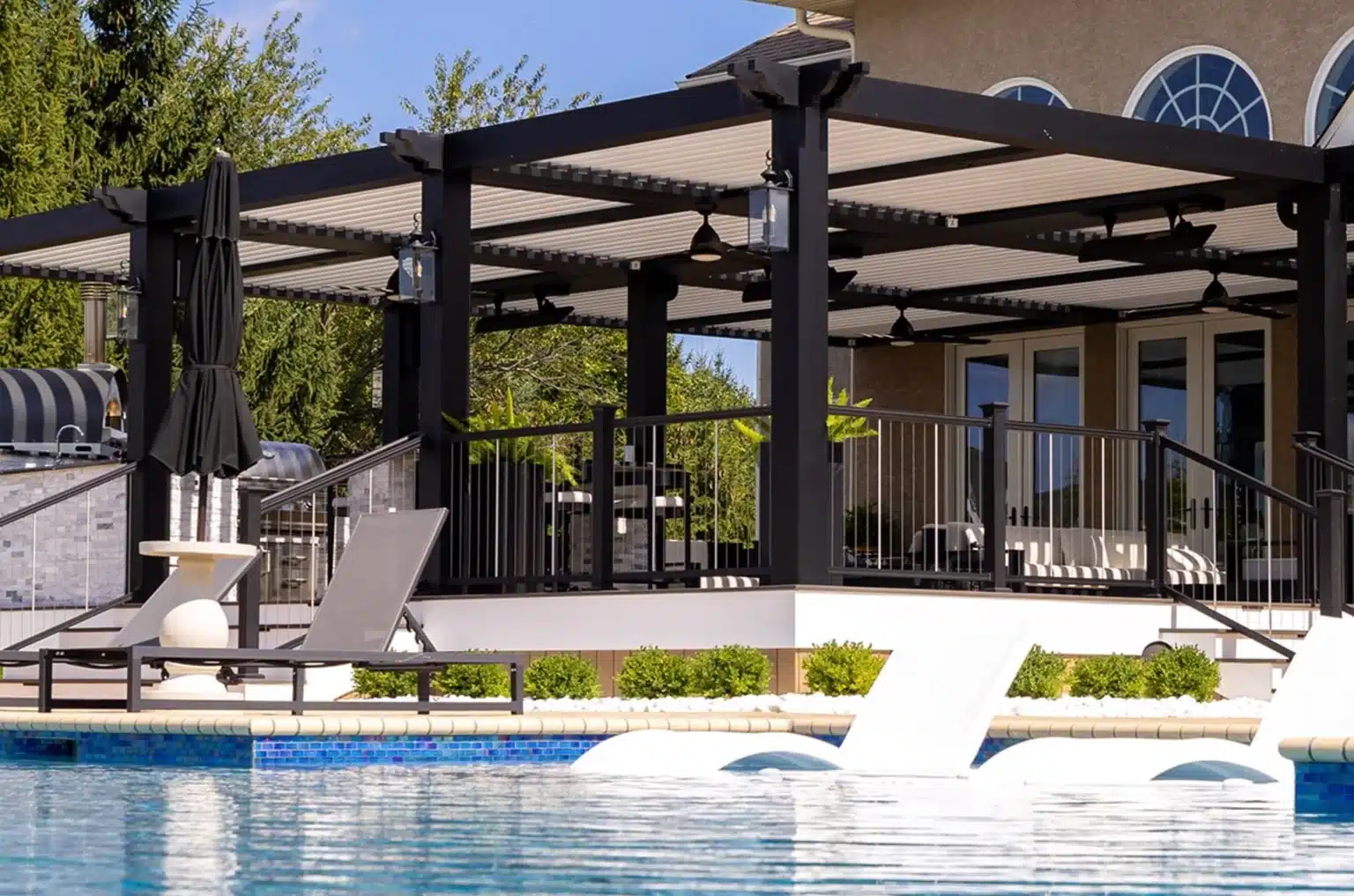 Modern aluminum pergola with overhead louvers beside a luxury residential swimming pool