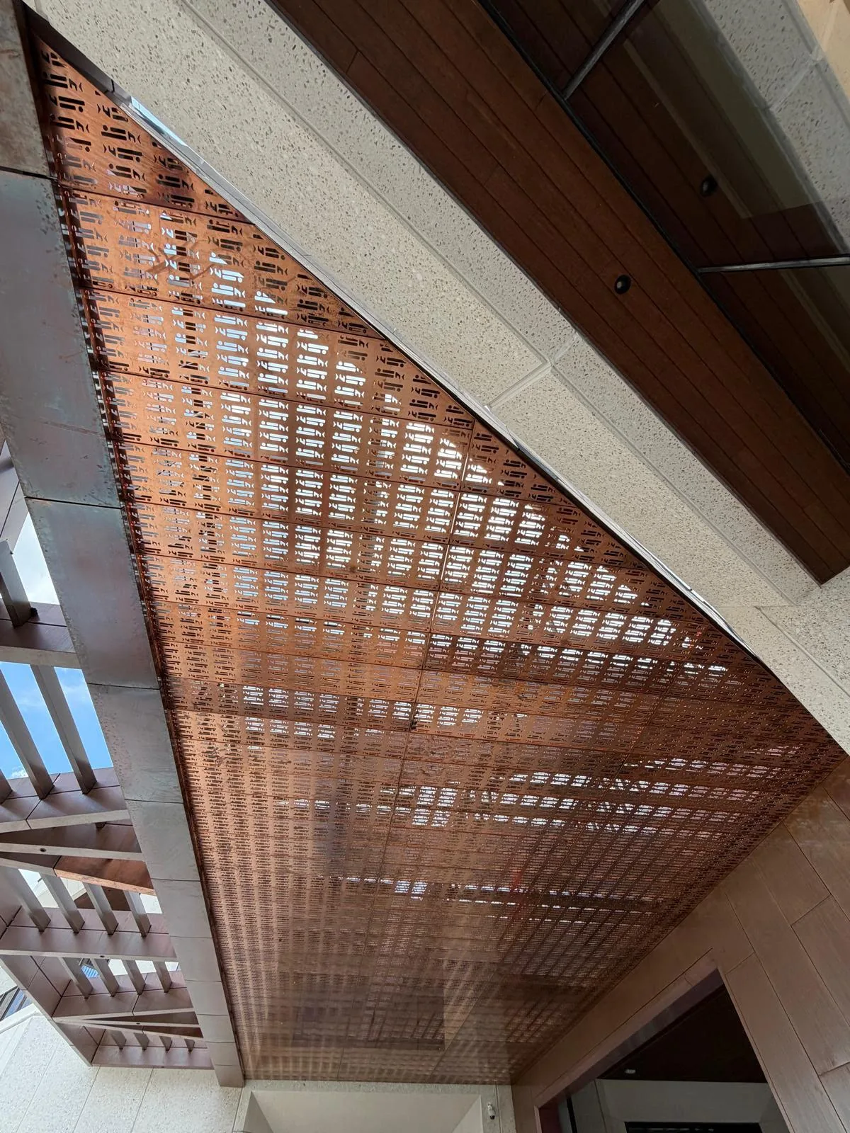 Copper tone perforated metal canopy viewed from below