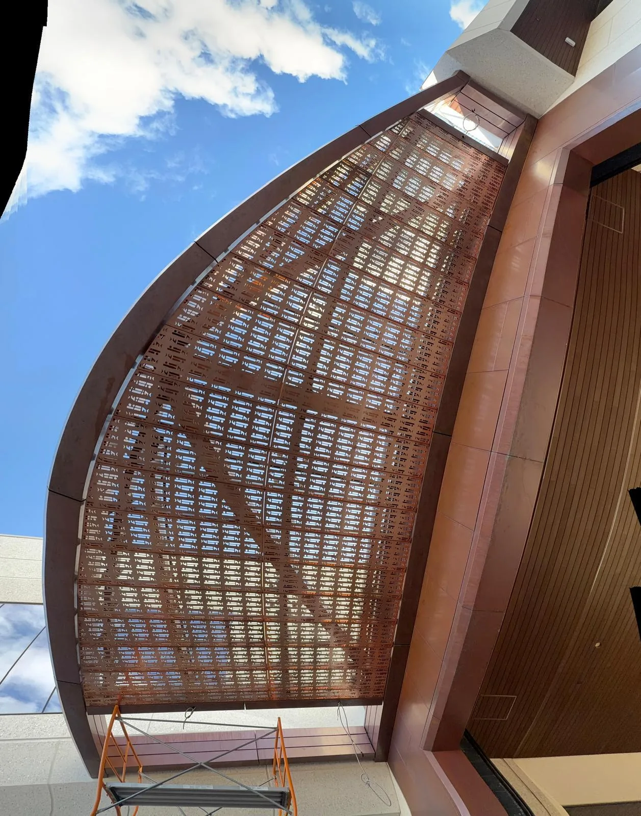 Exterior low angle view of a curved perforated metal canopy system