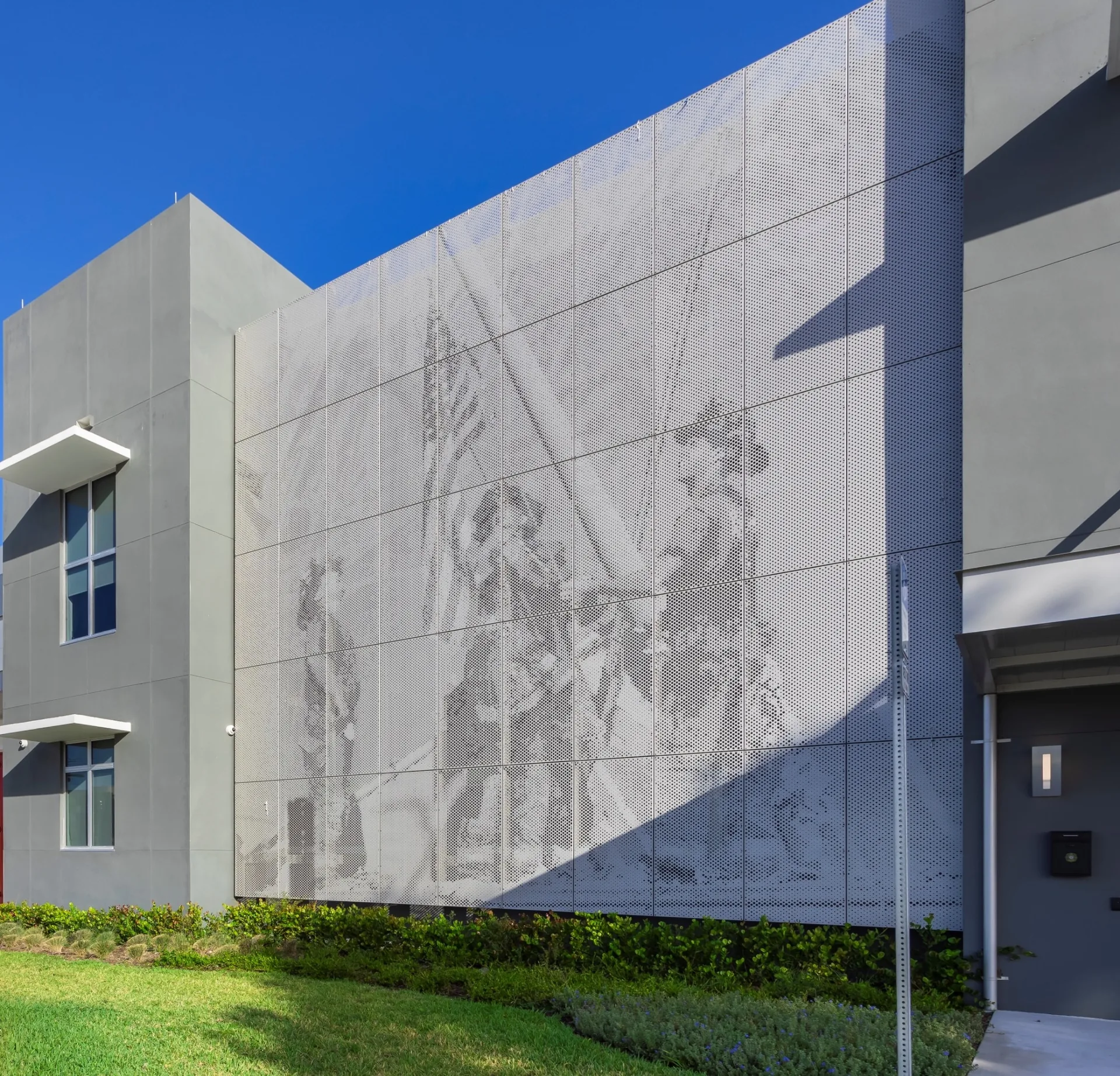 Perforated metal image panel facade creating a firefighter mural through varied perforation density